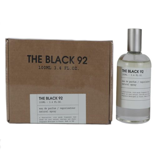 Frasco de perfume The Black 92 con diseño minimalista de vidrio transparente y tapa plateada, junto a una caja de cartón marrón con texto negro en negrita y detalles del producto.