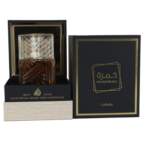 Khamrah Eau de Parfum 100ml de Lattafa, con un intrincado frasco de cristal con líquido ámbar y tapón geométrico transparente, que se muestra junto a su envase negro y dorado.