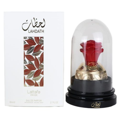 Pride Lahdath Eau de Parfum de Lattafa, con un exclusivo frasco en forma de rosa roja encerrado en una cúpula de vidrio con una base dorada decorativa, acompañado de una caja blanca adornada con patrones de hojas en rojo y dorado.