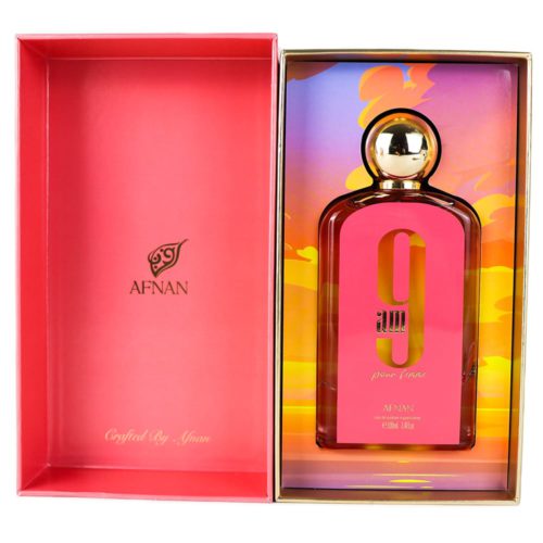 Una caja de perfume abierta que revela el frasco de «9 AM pour femme» en su interior. El envase interior tiene un colorido fondo degradado con tonos naranja, amarillo y morado, que complementa el tapón dorado del frasco.