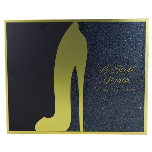 La parte frontal de la caja del set de regalo "Le Style Walk," con una silueta dorada de un tacón alto y un fondo negro brillante con texto que dice "Dubai to Miami."